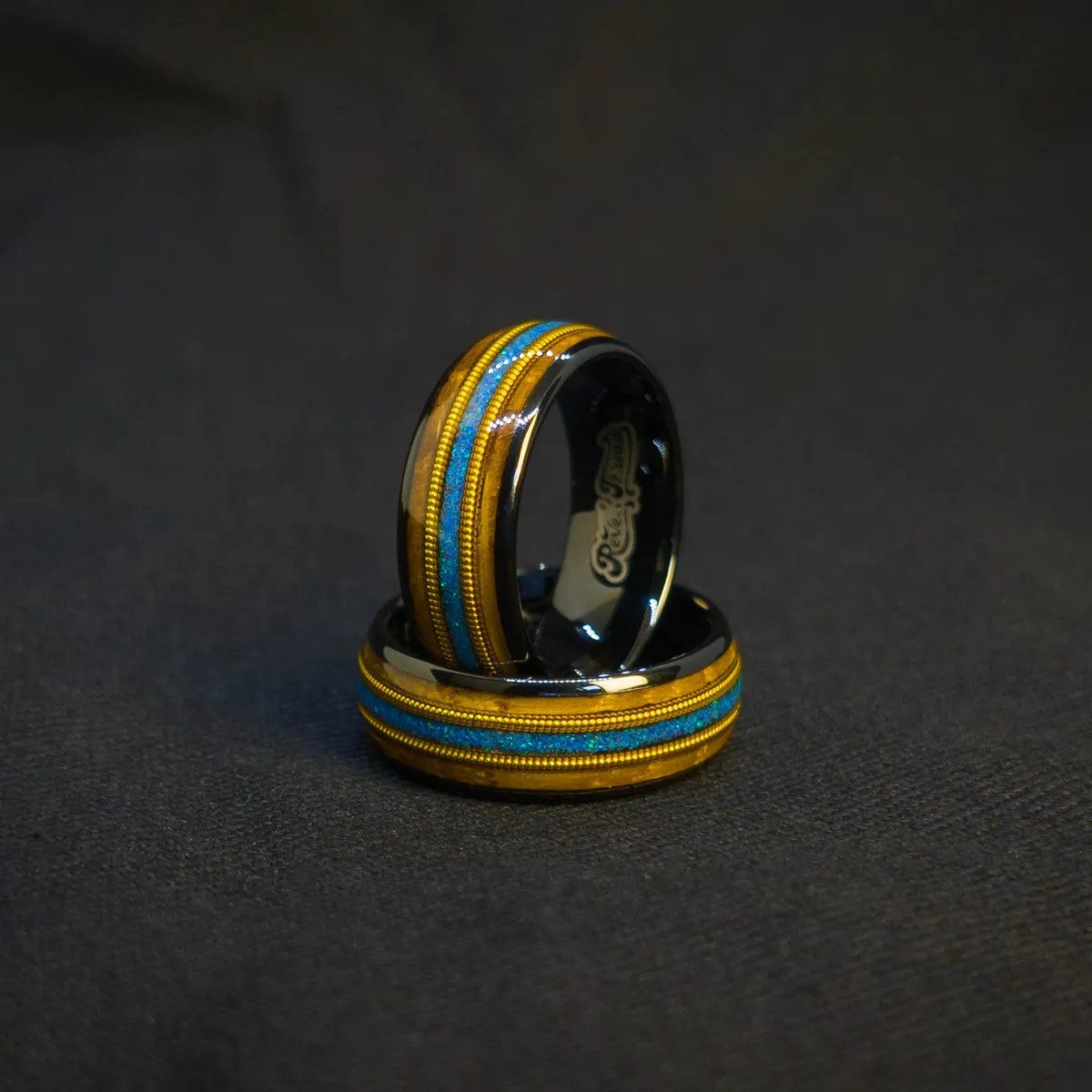 Ocean Fret Ring moody ocean-lit view, black metal base, whiskey barrel wood inlay, golden guitar string accent