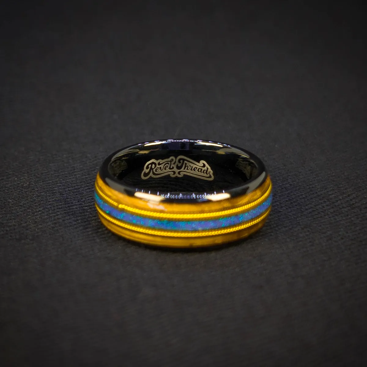 Ocean Fret Ring moody ocean-lit view, black metal base, whiskey barrel wood inlay, golden guitar string accent